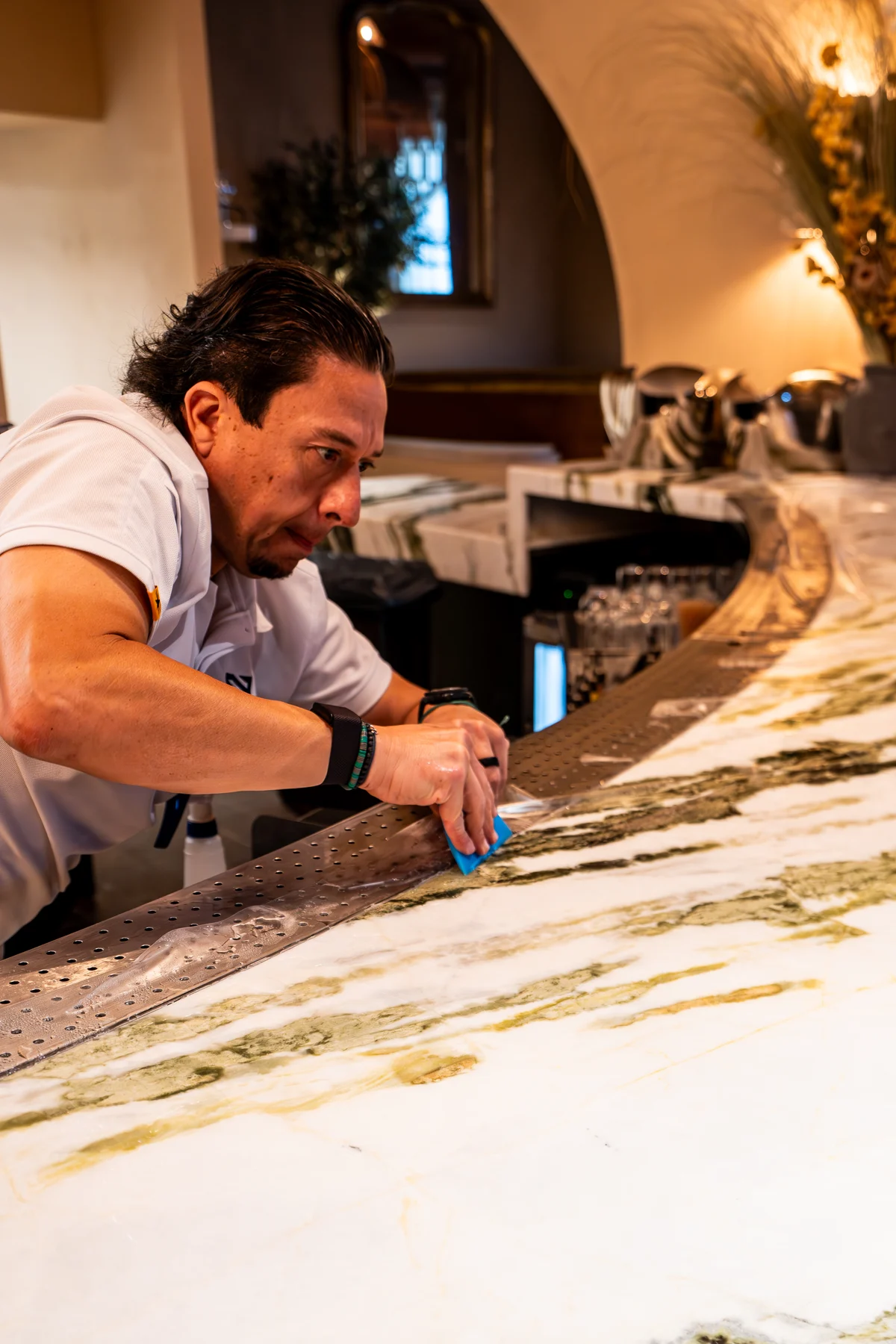 Premier Surface Protection technician applying clear protective film to a veined stone bar top