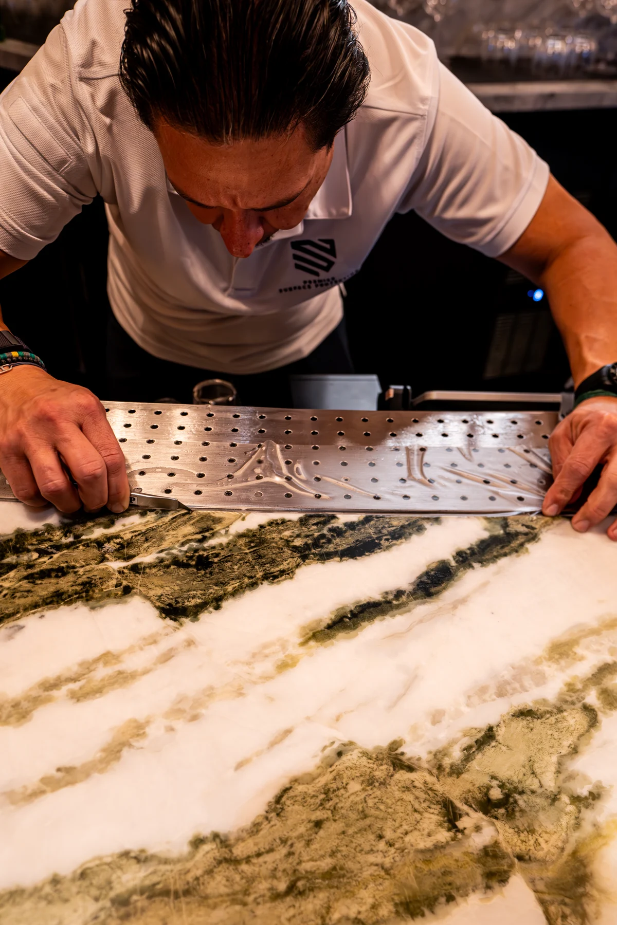 Close detail of Premier Surface Protection finishing clear protective film on a green-veined stone surface