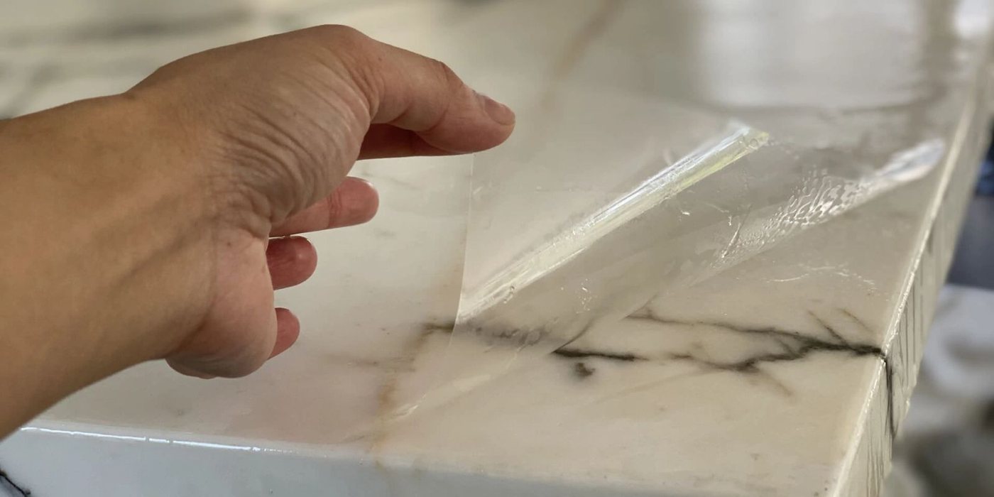 Close view of a film edge being trimmed along a stone countertop by Premier Surface Protection