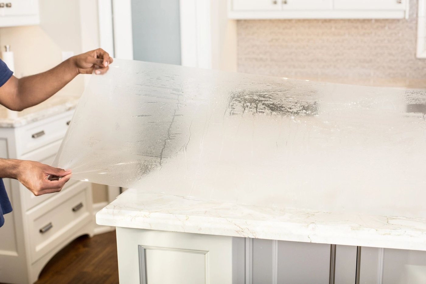 Premier Surface Protection installing countertop surface film, hands working the film flat