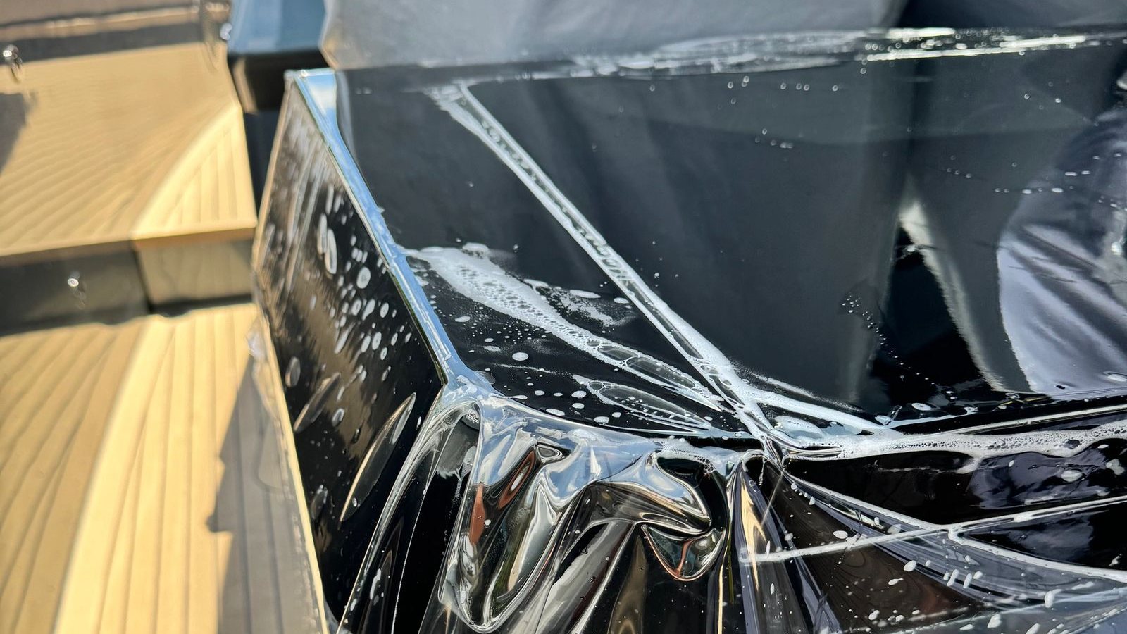 Premier Surface Protection applying clear film to a yacht surface above a teak deck