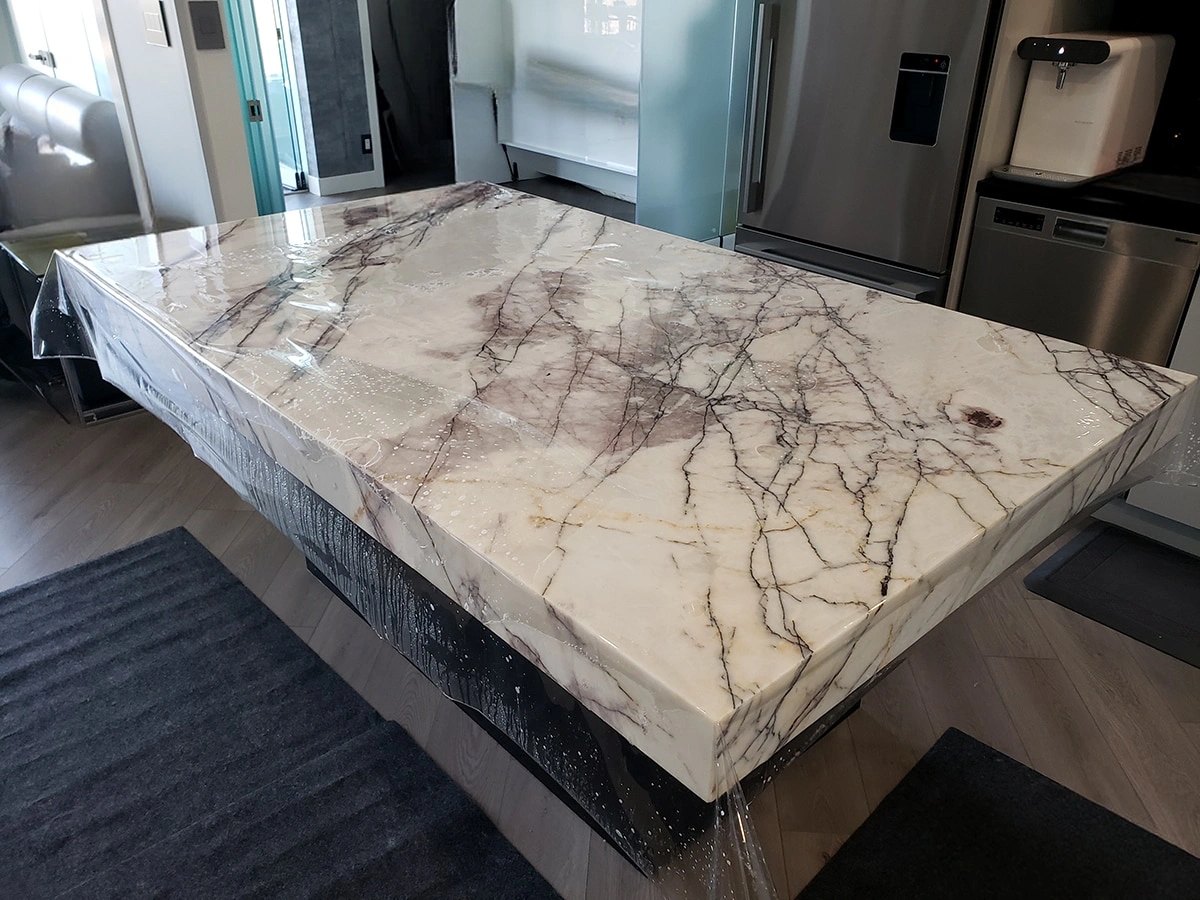 Premier Surface Protection installing countertop surface film on a veined quartzite island